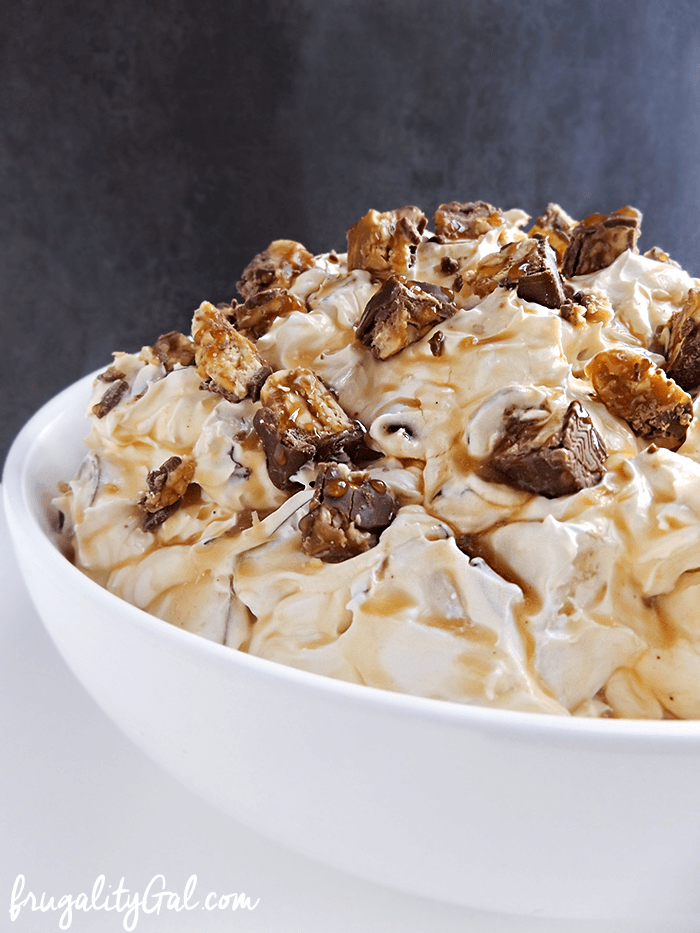 Side view of caramel Snickers salad in a white bowl.
