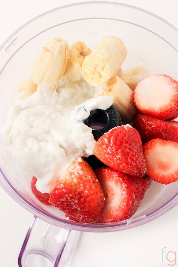 Top view of the food processor with ingredients for the sugar-free strawberry banana smoothie popsicles.