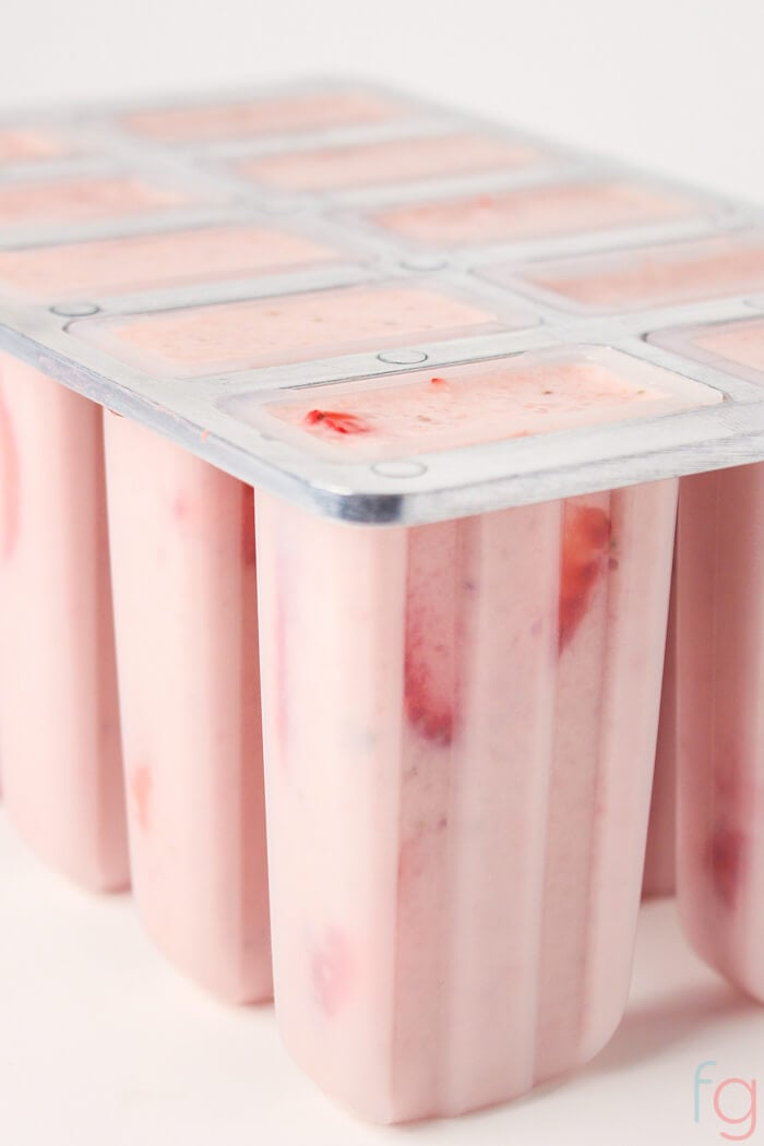 Popsicle molds filled with strawberry banana smoothie ready for freezing.