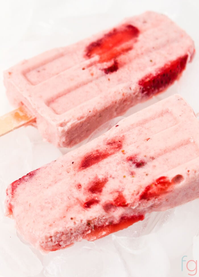 Two strawberry banana popsicle molds on a white table.