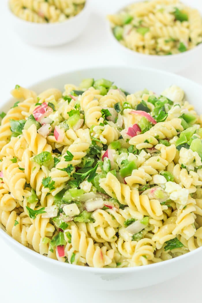 Mediterranean pasta salad with feta and fresh parsley in a white porcelain bowl.