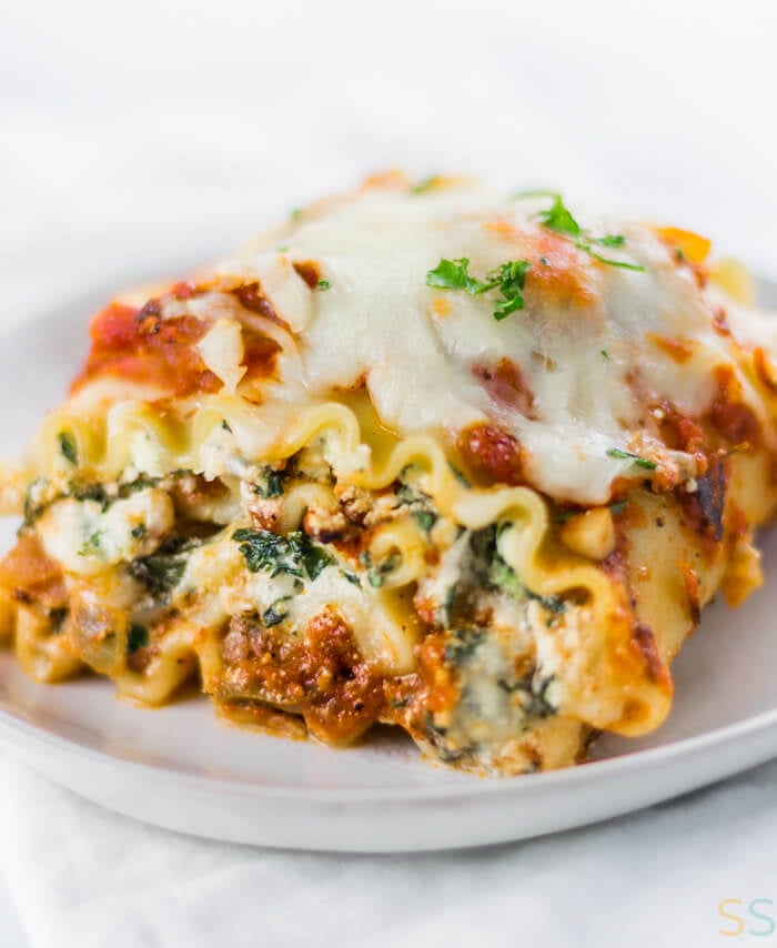A serving of spinach lasagna roll ups on a white plate.
