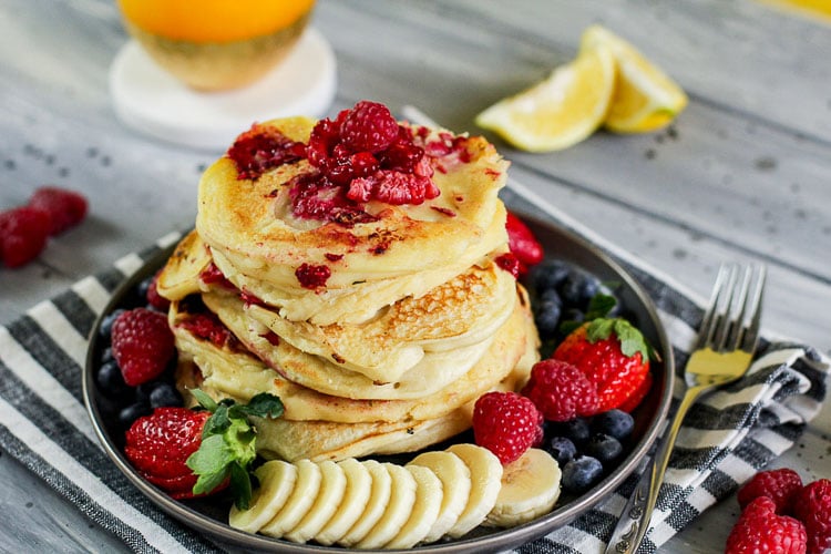 Plated Raspberry Lemon Ricotta Pancakes surrounded by fresh fruits