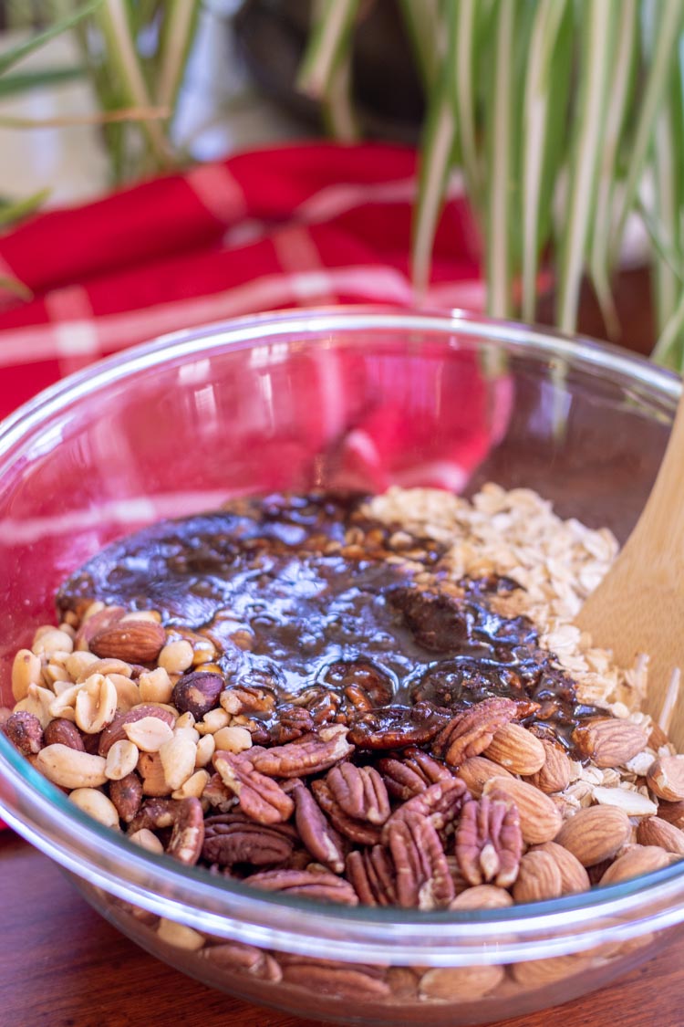 Glass bowl with nuts, oats and spices for homemade granola ready to be mixed together.