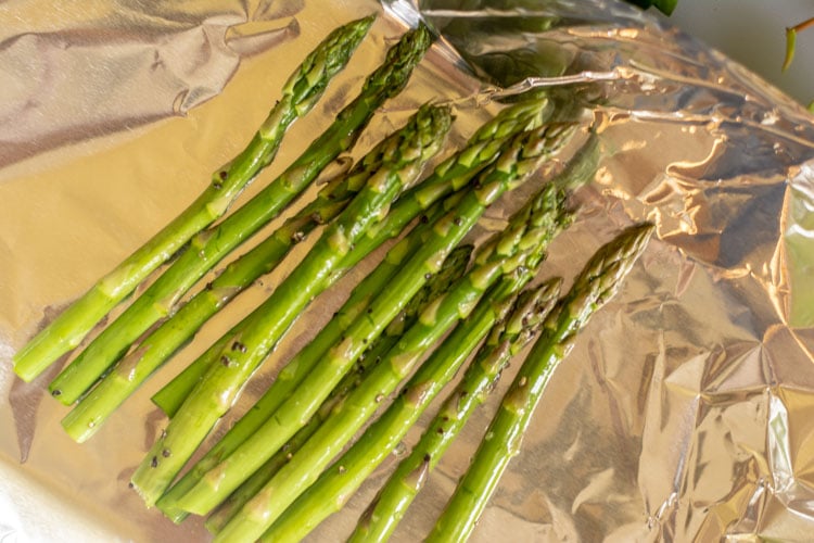 Several Spears of Asparagus on a piece of aluminum foil to make a bed for the salmon.