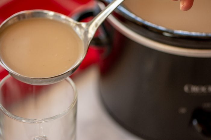 Ladle filled with christmas crock pot coffee being poured into a glass.