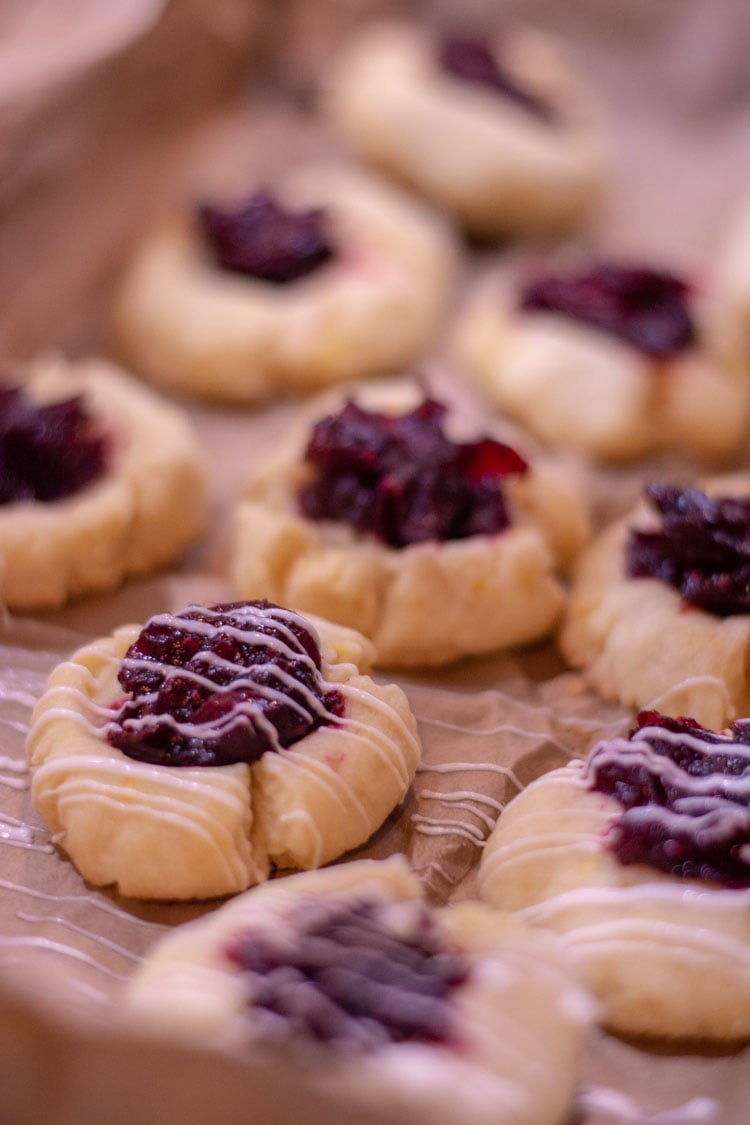 Baked cookies on butcher paper with white chocolate being drizzled on.