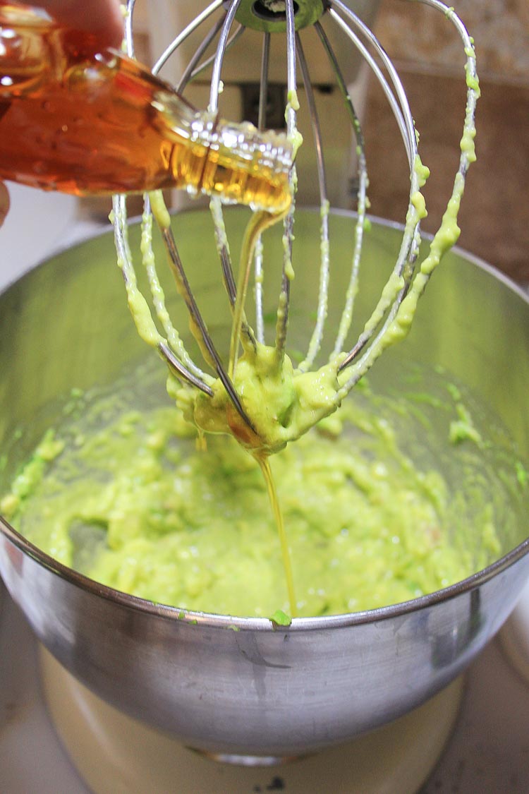 Adding maple syrup to the avocado in the mixing bowl.