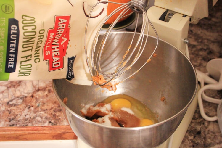Pouring in arrowhead organic coconut flour into the mixing bowl with the other ingredients.