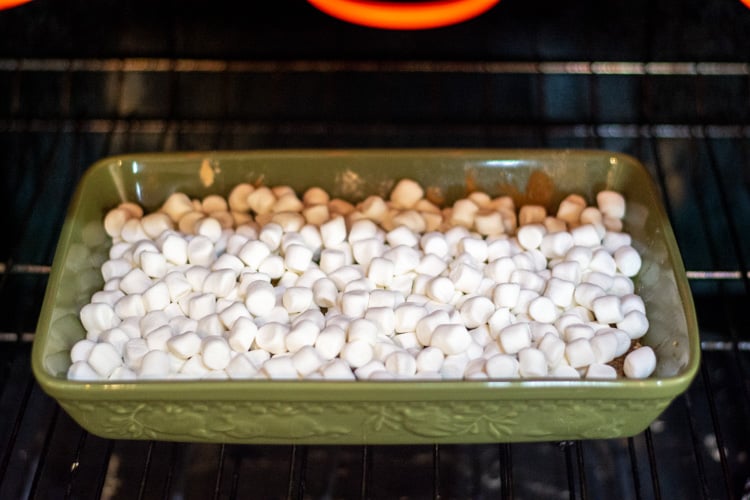 green pan in the oven with the cake mix and topped with marshmallows ready to be broiled.