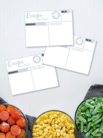 Free printable and editable freezer labels on a grey surface next to frozen veggies in bowls.