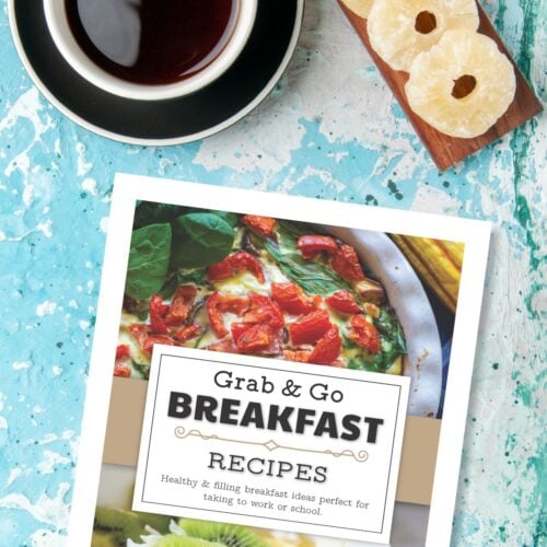 Cover of the free printable meal prep breakfast recipes ebook on a blue painted table next to coffee cup and candied pineapple rings.