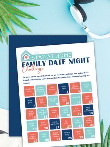 Free printable family date night challenge on a blue table next to palm leaves and headphones.