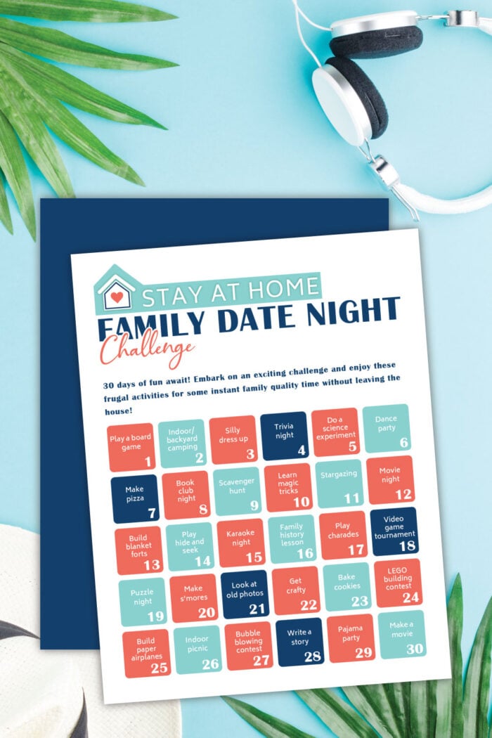 Free printable family date night challenge on a blue table next to palm leaves and headphones.