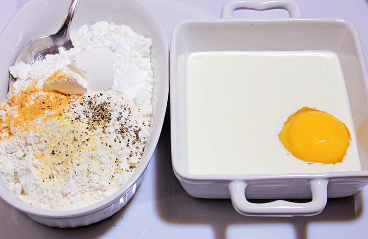 Two bowls, one with milk and egg, and one with flour and seasoning for the chicken wing coating.