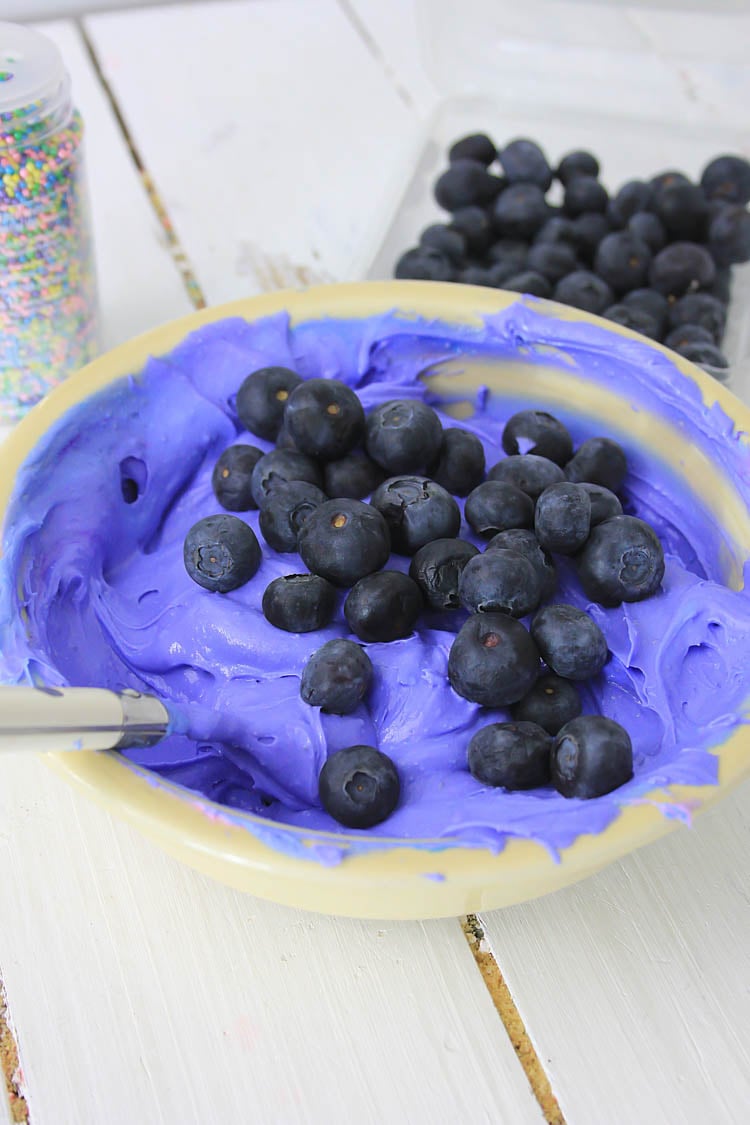 Blueberries and the cream cheese in a mixing bowl.