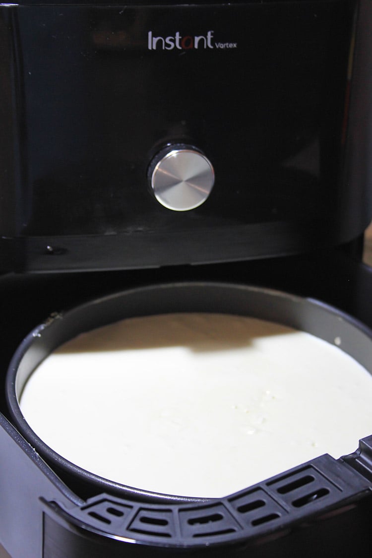 adding the cheesecake to the air fryer to be cooked.