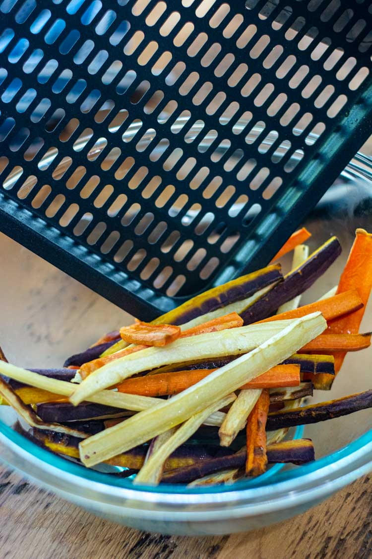 Adding the air fryer carrots to a glass bowl.