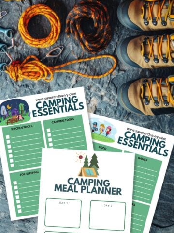 Free printable camping checklists and meal planner on a rugged surface next to hiking boots and gear.