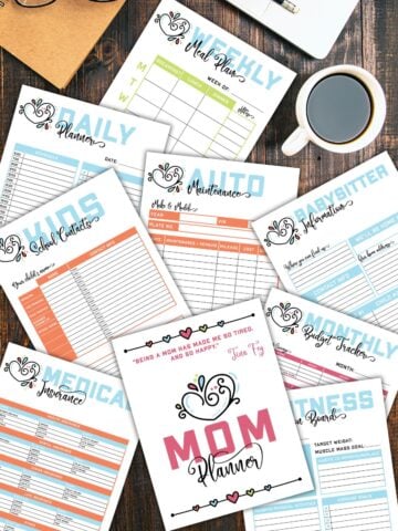 Printable planner pages from the mom binder on a wooden table next to laptop and a cup of coffee.