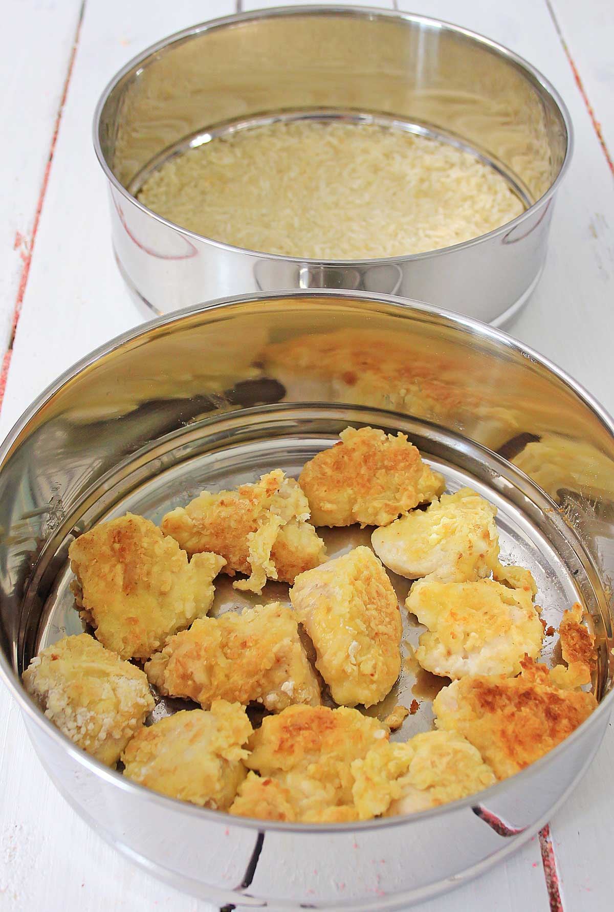 rice in one steamer tray and the chicken in the other tray.
