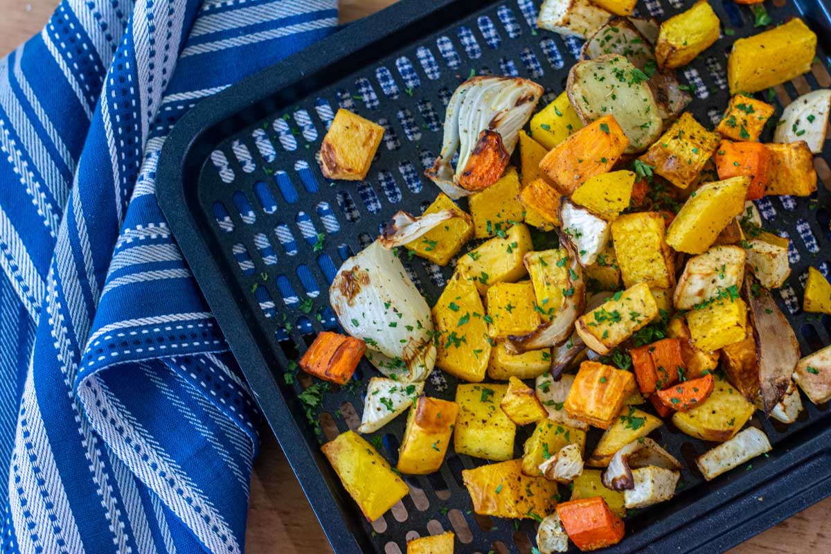 tray with roasted root vegetables and a blue cloth napkin.