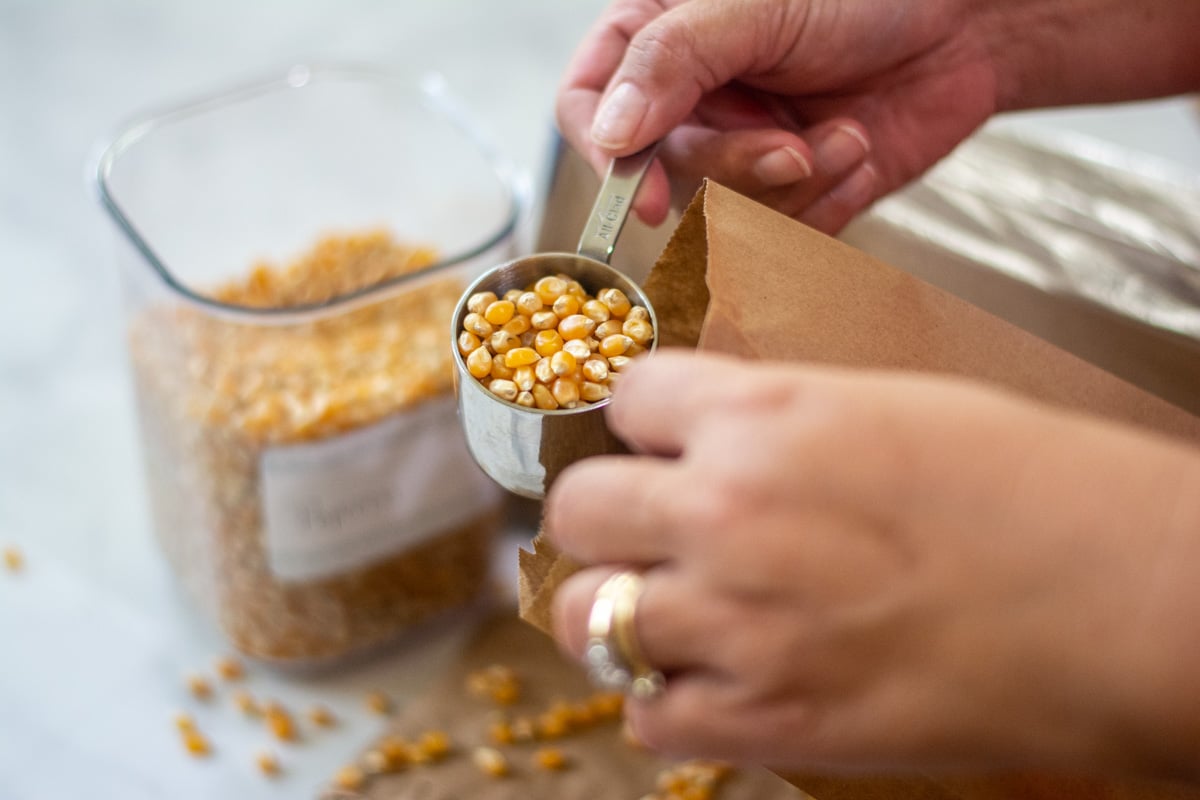 pouring the popcorn into the brown bag.