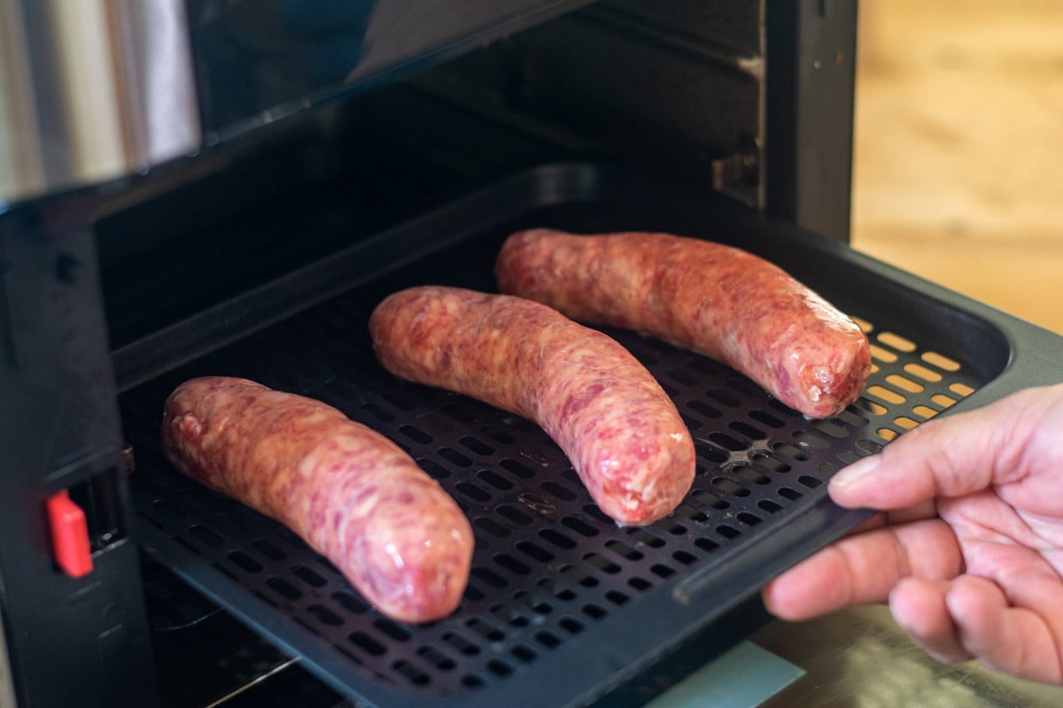 Inserting the beer brats into the air fryer.