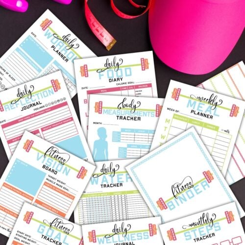 Several pages from the printable health and fitness binder next to workout equipment.
