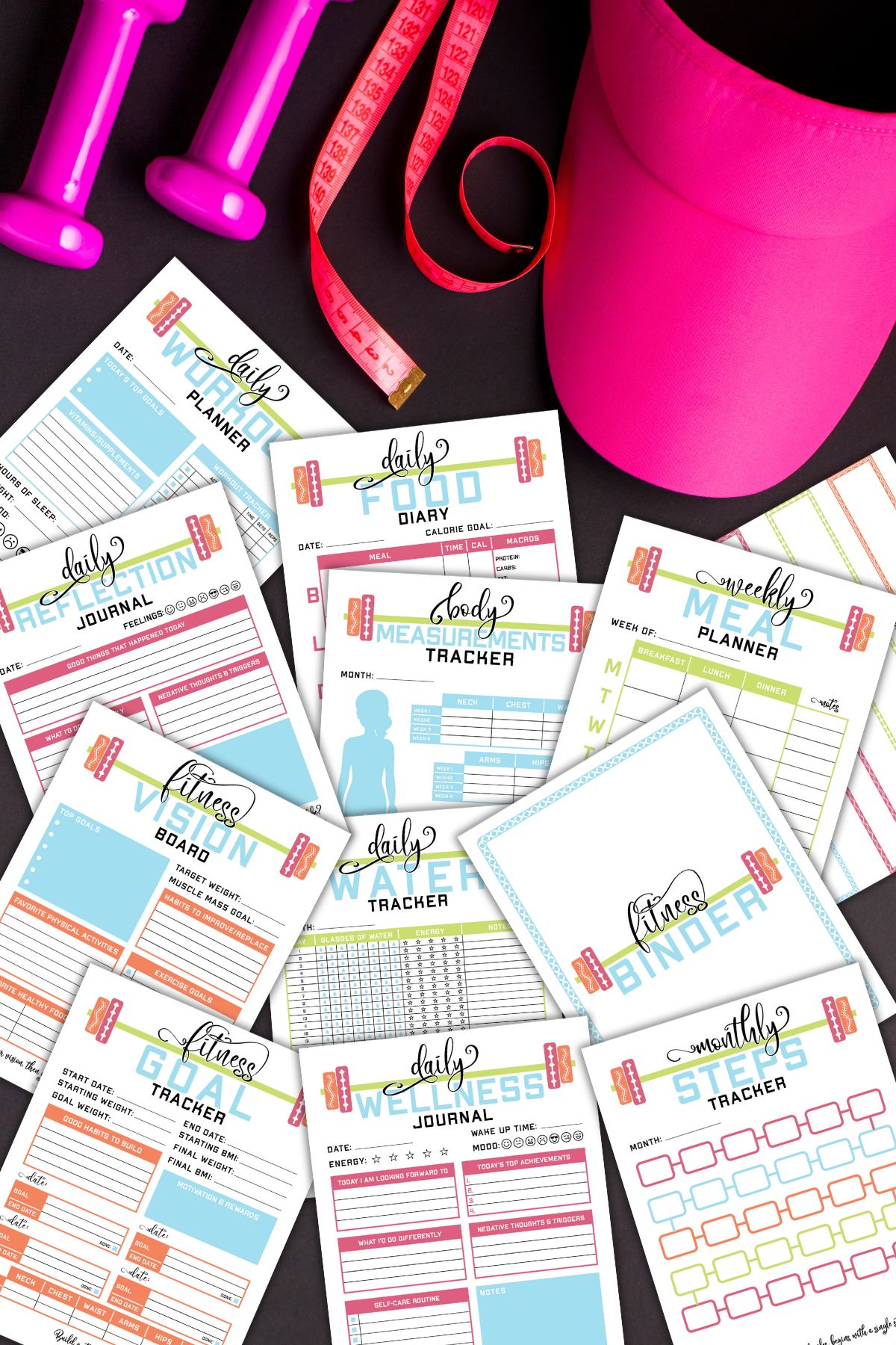 Several pages from the printable health and fitness binder next to workout equipment.
