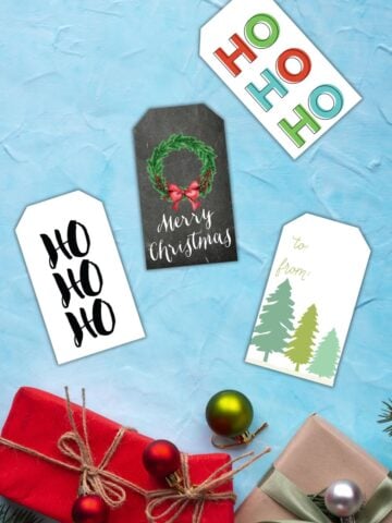 free printable Christmas gift tags on a blue table next to Christmas gifts.