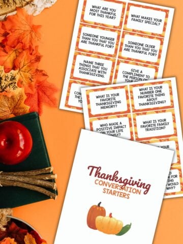 Top view of free printable Thanksgiving conversation starters on an orange background next to autumn decor.