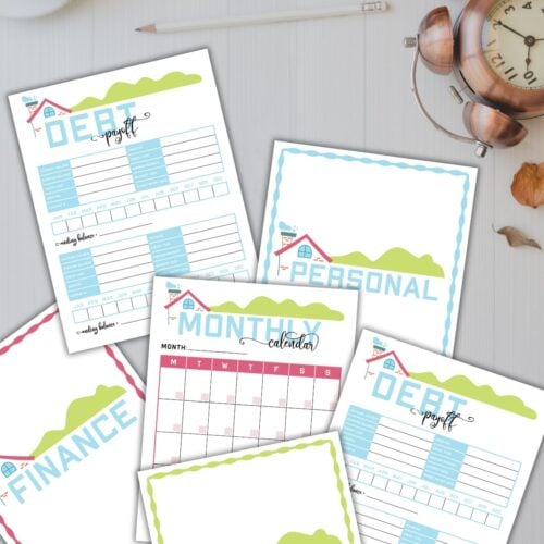 printable sheets from the home management binder on a table next to a clock and a cup of tea.