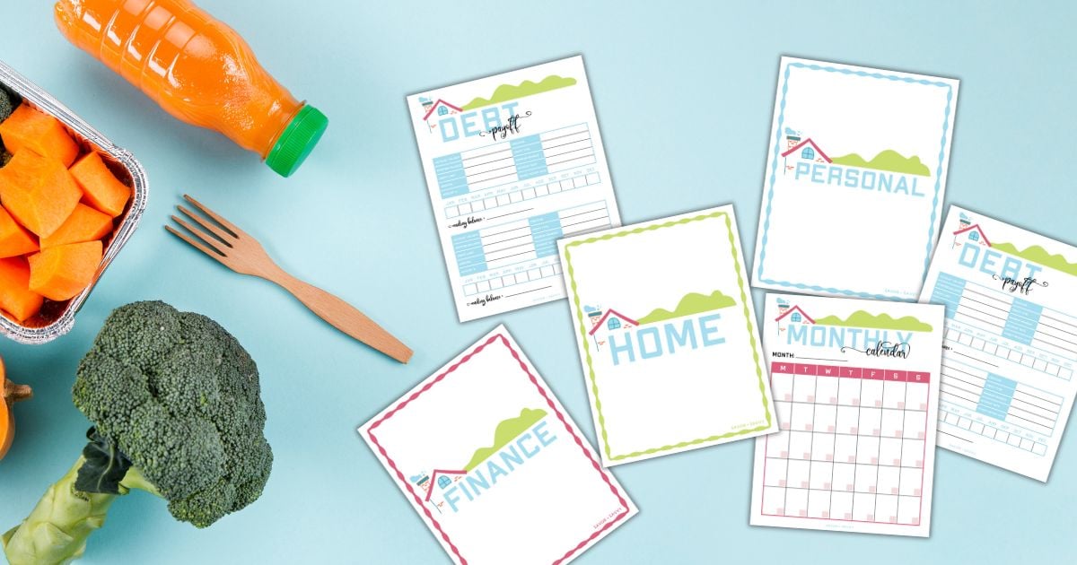 sheets from the printable home management binder on a blue table next to fresh veggies.