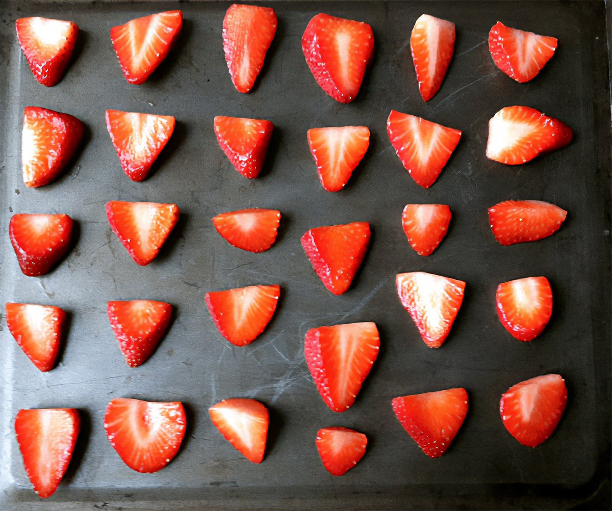 top view of sliced fresh strawberries on a sheet pan.