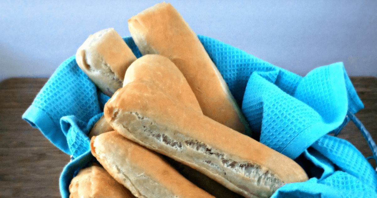 Homemade breadsticks in a basket lined with a blue kitchen towel.