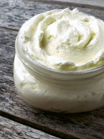 Homemade fresh butter in a jar on a wooden table.