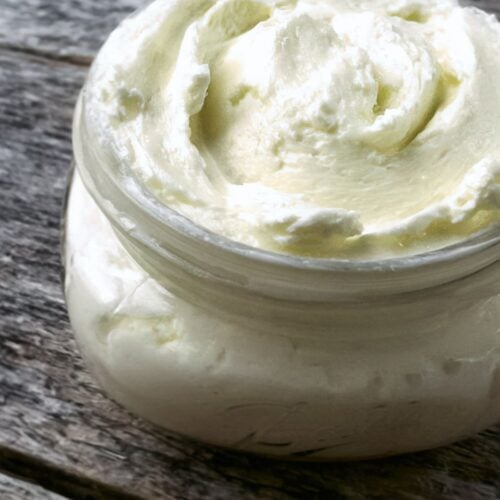 Homemade fresh butter in a jar on a wooden table.