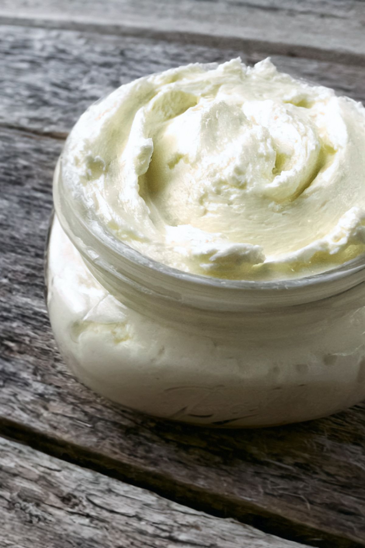 Homemade fresh butter in a jar on a wooden table.