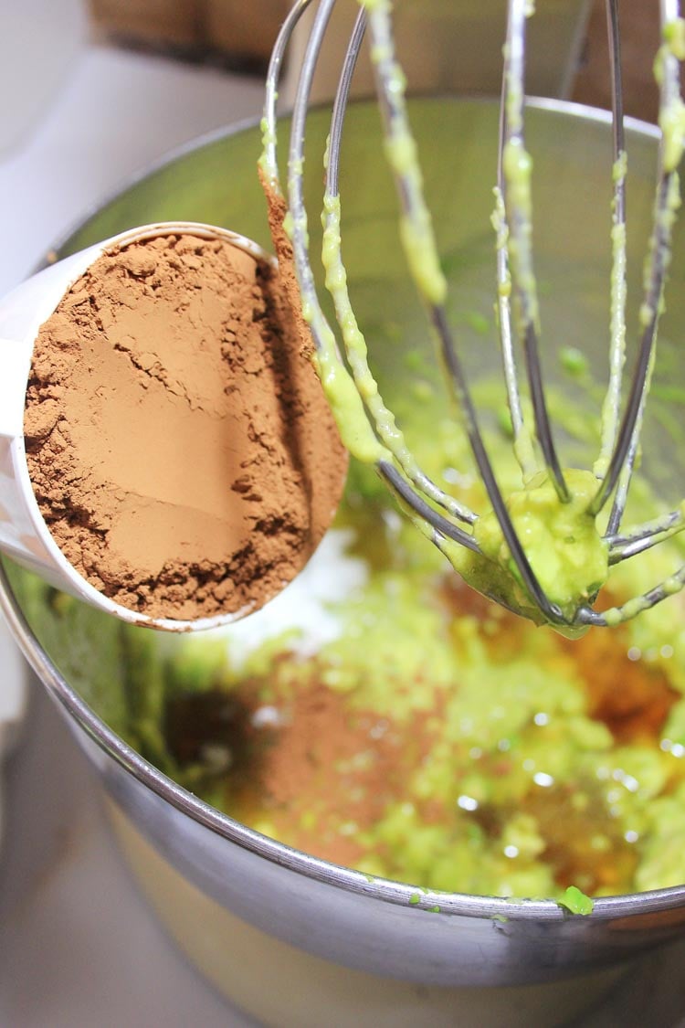 adding cocoa powder and sugar to the avocado in the mixing bowl.
