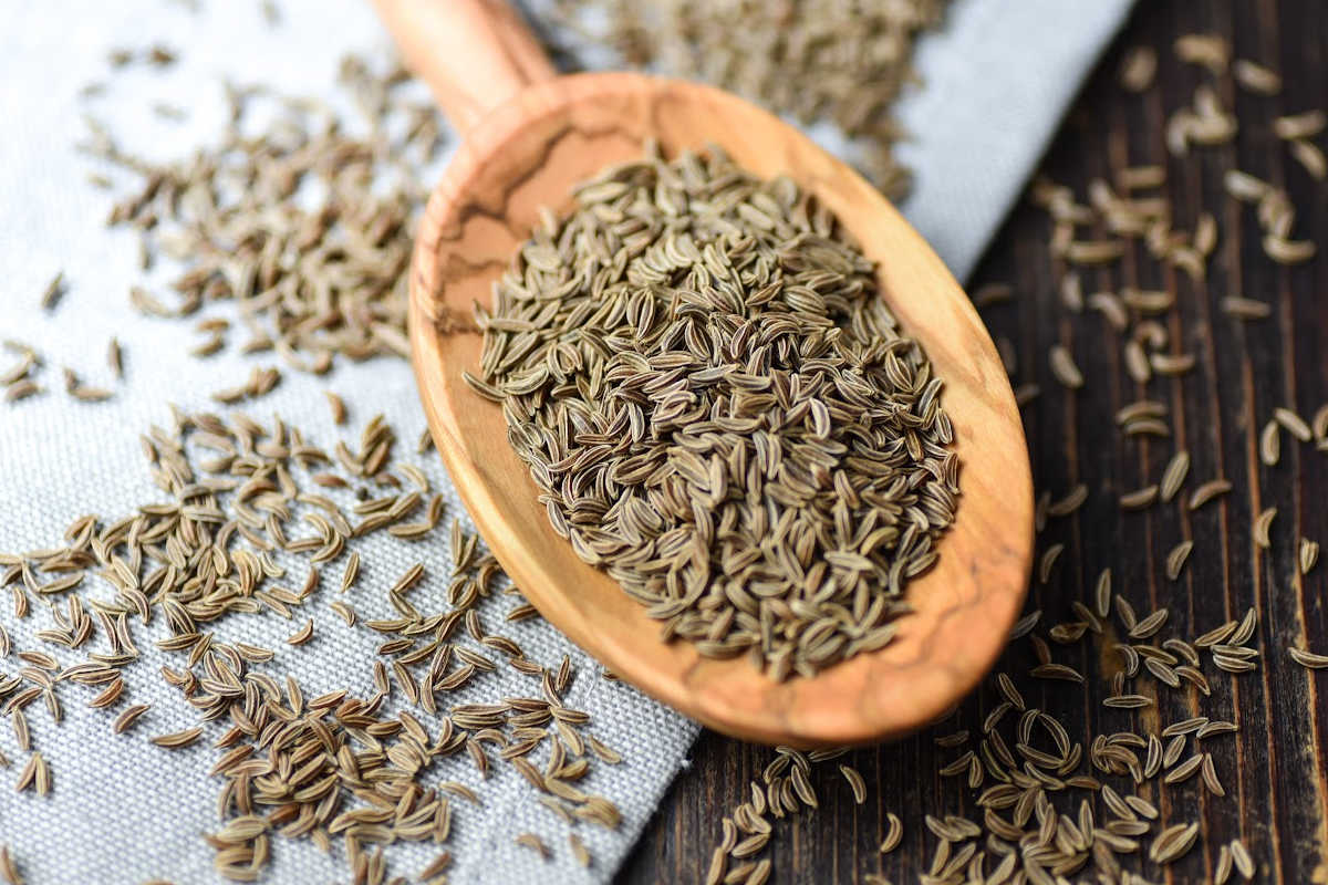 top down view of wooden spoon filled with caraway seeds.