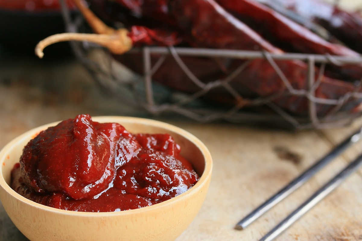 wooden bowl with gochujang and chopsticks and peppers.