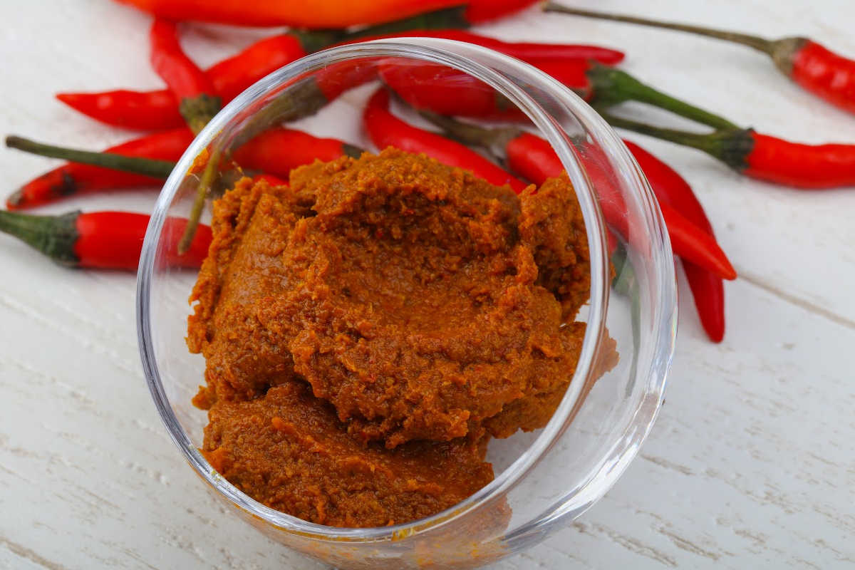 glass bowl with harissa paste and peppers on a white table.