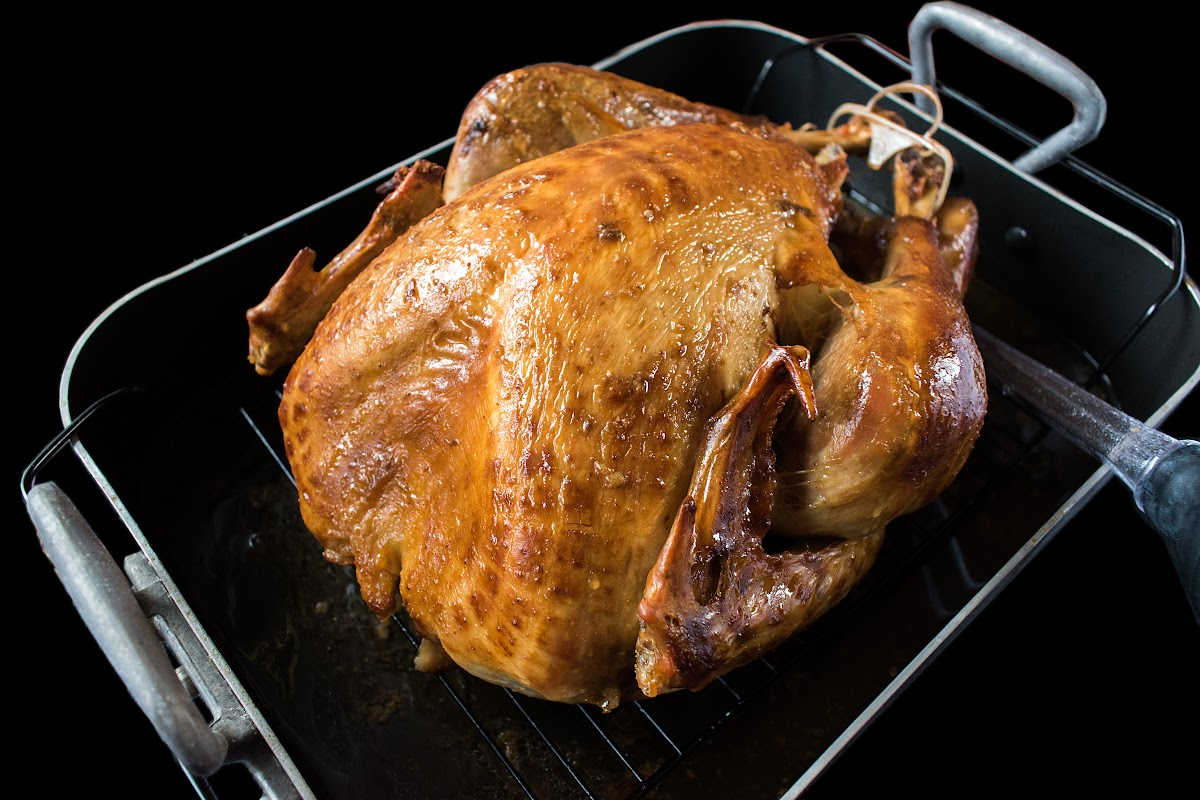 roasted turkey in a baking dish with a basting tool.