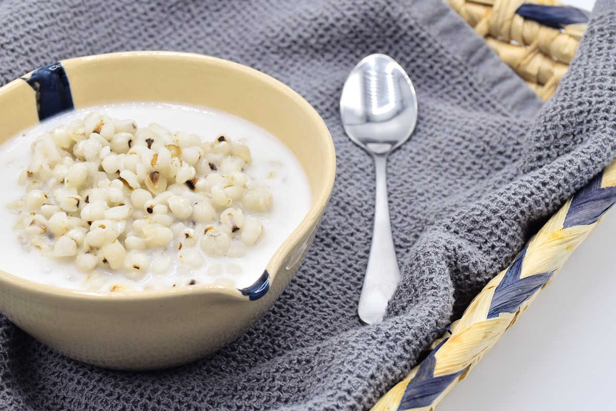 coconut aminos in a beige bowl with a spoon next to it.