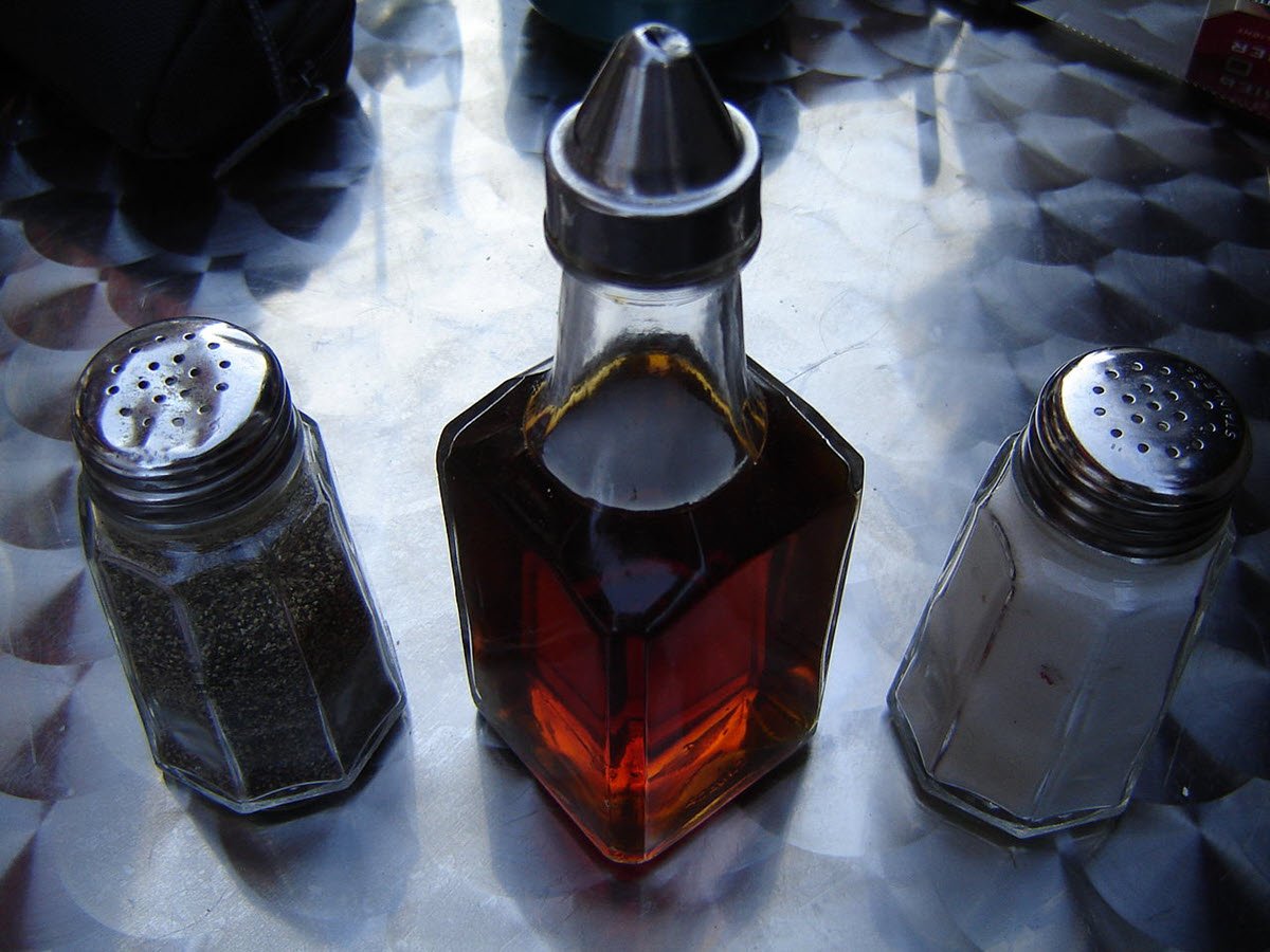 Malt vinegar in glass bottle with salt and pepper shakers.