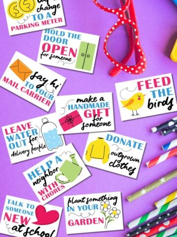 Free printable random acts of kindness cards for kids on purple background next to glasses and school supplies.