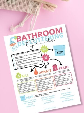 Free printable bathroom decluttering guide on a pink background next to eco friendly toothbrushes.