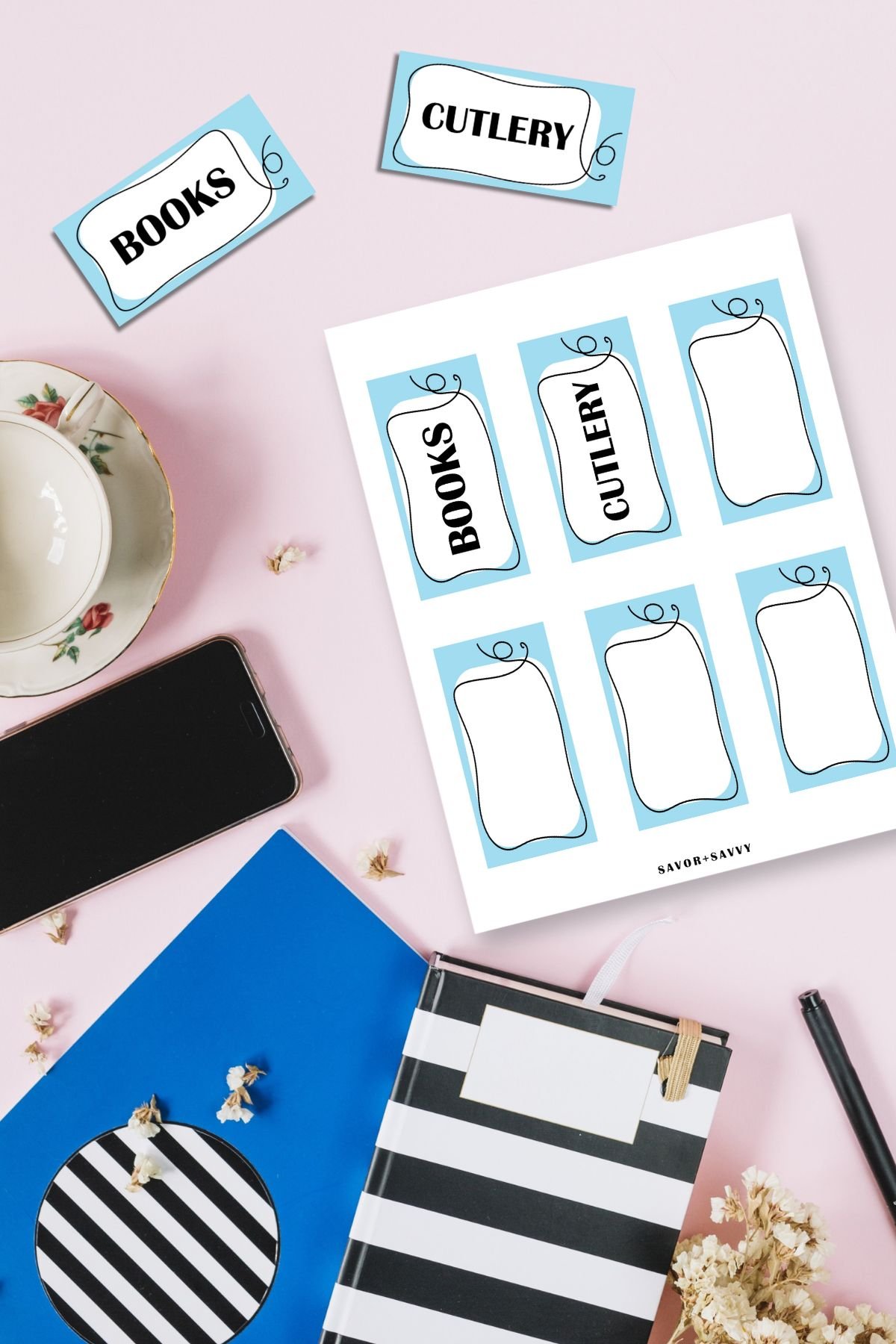 Medium 4x2 inch storage bin labels on pink background next to notebooks.
