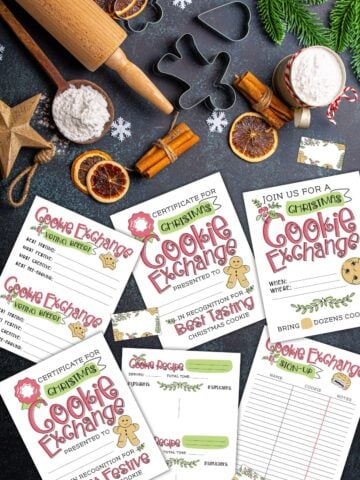Free Christmas cookie exchange printables on a black table next to baking supplies and Christmas decor.